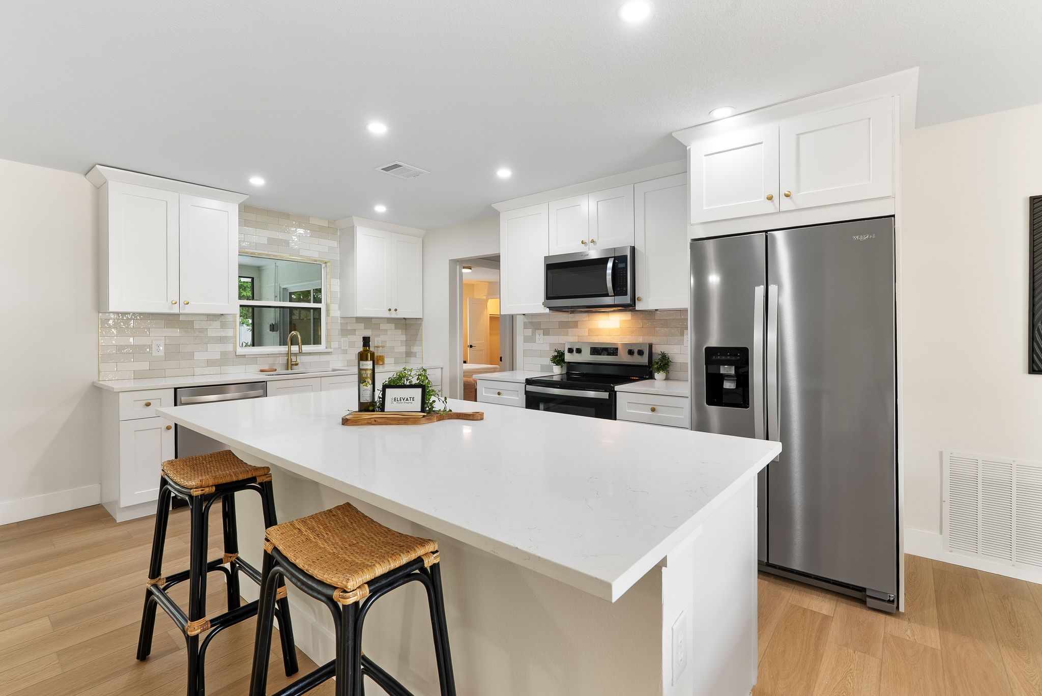 Kitchen after - white shaker cabinets, quartz island, subway tile backsplash
