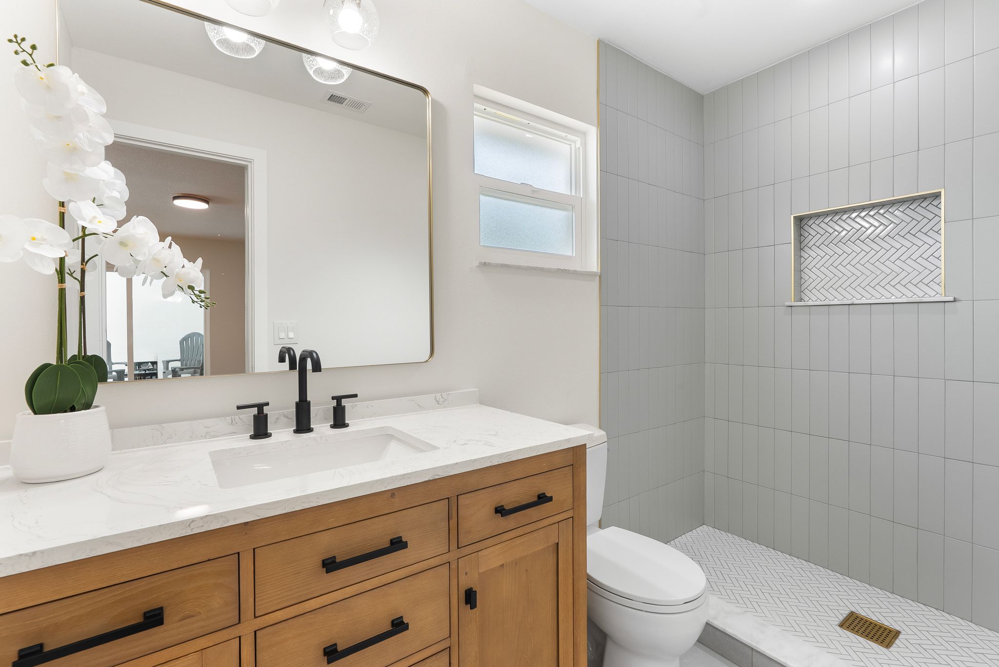 Primary bathroom after - wood vanity, quartz counter, herringbone tile walk-in shower