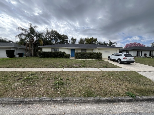 Brenda Dr exterior before - dated yellow paint, overgrown landscaping